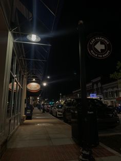 an empty city street at night with cars parked on the sidewalk