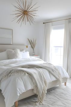 a bedroom with white bedding, pillows and a starburst hanging from the ceiling