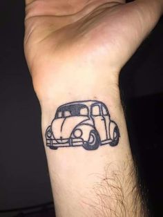 a small black and white car tattoo on the wrist