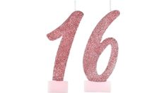 the number sixteen candle has pink glitter on it and is in front of a white background