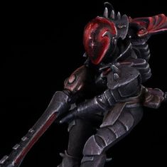 a toy figurine is posed on a black background with red eyes and horns