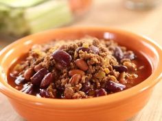 a bowl filled with chili and beans on top of a wooden table