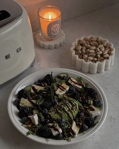 a white plate topped with fruit and vegetables next to an air freshenerer filled with nuts