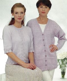 two women standing next to each other wearing sweaters