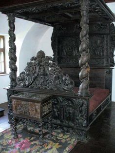 an ornate wooden bed sitting on top of a rug