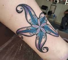 an artistic tattoo on the arm of a woman with blue and purple flowers in it