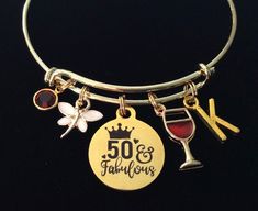 a close up of a wine glass on a metal bracelet with charms and an inscription that reads 50 fabulous