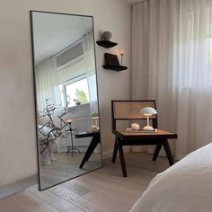 a mirror sitting on top of a wooden floor next to a table with a lamp