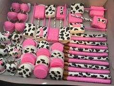 a box filled with lots of pink and black cupcakes covered in frosting