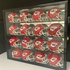 a display case filled with football helmets on top of a white countertop next to a black wall