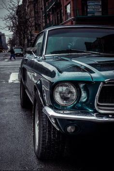 an old car is parked on the side of the road in front of some buildings