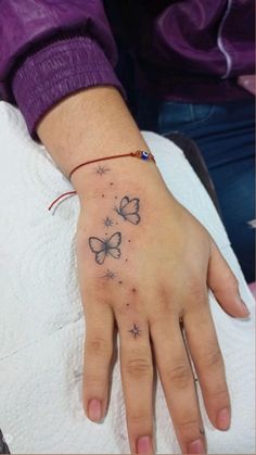 a woman's hand with two butterflies on it and stars in the sky tattoo