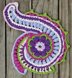 two crocheted doily on wooden planks, one purple and the other green