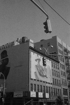 a traffic light hanging over a city street next to tall buildings with billboards on them