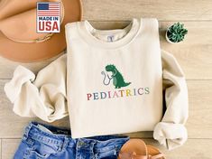 Embroidered Pediatrics Sweatshirt, Ped Crewneck Nurse Sweatshirt, Pullover Pediatrics Sweatshirt, Cute Ped Sweatshirt, Pediatrics Sweatshirt ⭐ Exclusive Embroidery & Printing - Customize your business name in your preferred font. For custom logos, contact us for a quote based on the design's complexity. ⭐ PRODUCT SPECIFICATIONS: SWEATSHIRT: 8-ounce, 50/50 cotton/poly Double-needle stitching at waistband and cuffs Double-lined hood with dyed-to-match drawcord 1x1 rib knit cuffs and waistband with spandex Front pouch pocket Safety Green is compliant with ANSI/ISEA 107 high-visibility standards Recycled, high-performing black tear-away label SHIRT: 4.5-ounce, 100% ring spun US cotton 90/10 ring spun cotton/poly (Antique Cherry Red, Antique Heliconia, Antique Sapphire, and Sport Grey) 50/50 ri Face Ref, Peds Nurse, Respiratory Therapy, Pediatric Nurse, Black Tears, The Nurse, Silly Goose, Nurse Sweatshirt, Embroidered Crewneck