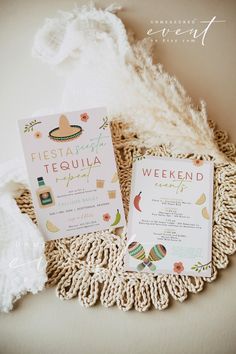 the wedding stationery is laid out on top of a doily with a white feather