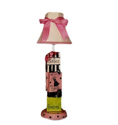 a lamp that is on top of a wooden stand with a pink ribbon around it