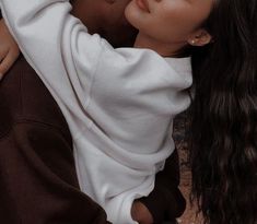 a man and woman kissing each other while sitting on the ground with their arms around each other