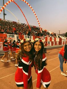 two cheerleaders pose for a photo in front of an audience