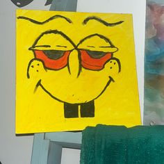 a yellow piece of art with red glasses on it and a green towel next to it