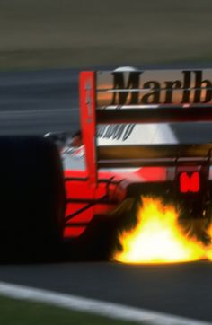 a red race car with flames coming out of it's tires on a track