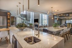 a kitchen with marble counter tops and an island in front of the sink, surrounded by chairs