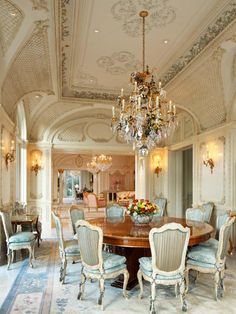 a large dining room with chandelier and blue chairs