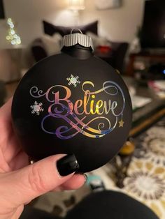 someone is holding up a black ornament with the word believe painted on it