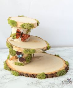 three tiered cake stand with moss and butterflies on it