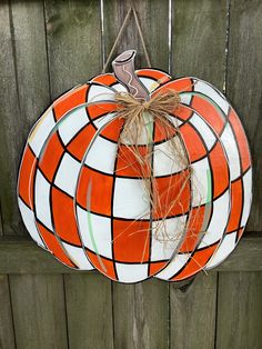 an orange and white pumpkin hanging on a fence