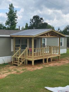 a small house with a metal roof and wooden steps leading up to the front porch