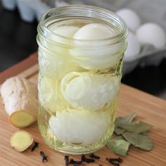 a mason jar filled with eggs and garlic on top of a wooden cutting board