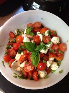 a white bowl filled with tomatoes, mozzarella and spinach on top of a stove