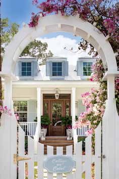 a white house with pink flowers on the front door and steps leading up to it