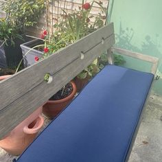 a blue bench sitting on top of a wooden deck next to potted plants and flowers