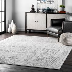 a living room with a large rug and two chairs