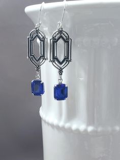 These Deco dangles are the perfect earrings for a 1920s themed wedding or party.  Sapphire blue vintage glass beads dangle from antiqued silver-plated brass Art Deco style connectors. The blue color is a medium blue. The silver-plated brass stamping connectors have an ornate front and a reverse side that is slightly hollow. (SEE 2nd PHOTO) These earrings are lightweight yet sturdy, lobe-friendly, and free of lead and nickel. The earrings measure 2 1/4 inches long from the top of the ear wires to the bottom of the glass beads. They hang from silver plated lever back ear wires. A versatile classic design that can be worn for weddings or work.  ABOUT THIS COLLECTION The sophisticated style of the Roaring Twenties is timeless. The sparkling crystal and luminous pearl jewels in this collection Victorian Dangle Earrings For Party, Blue Art Deco Wedding Earrings, Victorian Dangle Chandelier Earrings For Parties, Victorian Chandelier Dangle Earrings For Party, Victorian Style Party Chandelier Earrings, Handmade Elegant Earrings For Vintage Style, Art Deco Dangle Chandelier Earrings For Formal Occasions, Antique Nickel-free Earrings For Party, Victorian Style Nickel Free Earrings For Party