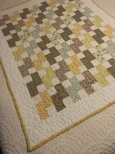 a quilt is laying on top of a bed with yellow and green squares in the middle