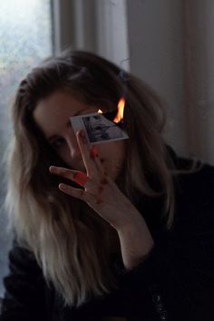 a woman is holding up her hand with fire coming out of the middle of her face