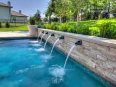 an outdoor swimming pool with water jets running from it's sides to the side