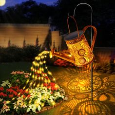 an illuminated watering can in the middle of a garden