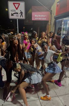 a group of young women dancing on the sidewalk in front of a street sign that says here to be