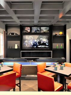 a room with tables, chairs and a television on the wall in front of it