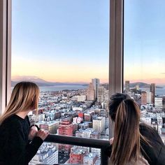 two women looking out the window at cityscape