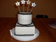 a three tiered cake with stars on top and numbers on the side sitting on a table