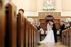 a bride and groom kissing in front of the pews