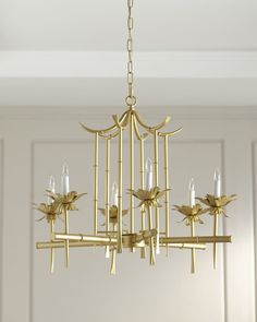 a gold chandelier hanging from the ceiling in a room with white walls and flooring