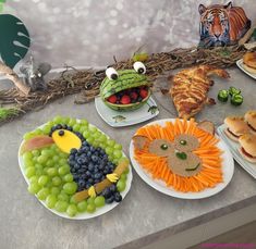 a table topped with plates filled with food and animals on top of each plate covered in fruit