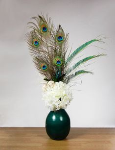 a vase filled with white flowers and peacock feathers