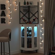 a lighted display cabinet in the corner of a room with bottles and glasses on it